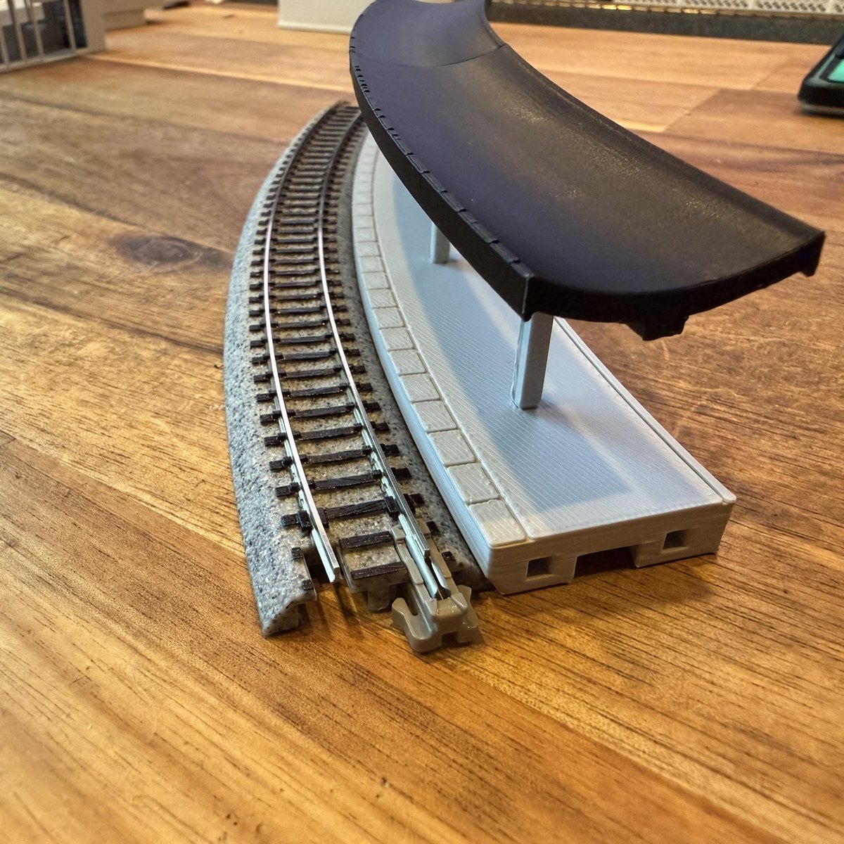 Real print: the platform end with its peg and dovetail pockets, pillars and canopy, next to the Unitrack roadbed